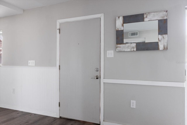 interior space with a wainscoted wall, wood finished floors, and visible vents