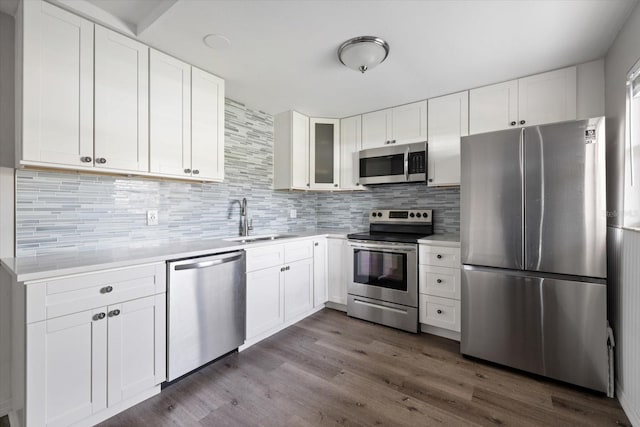 kitchen featuring dark wood finished floors, stainless steel appliances, tasteful backsplash, light countertops, and a sink