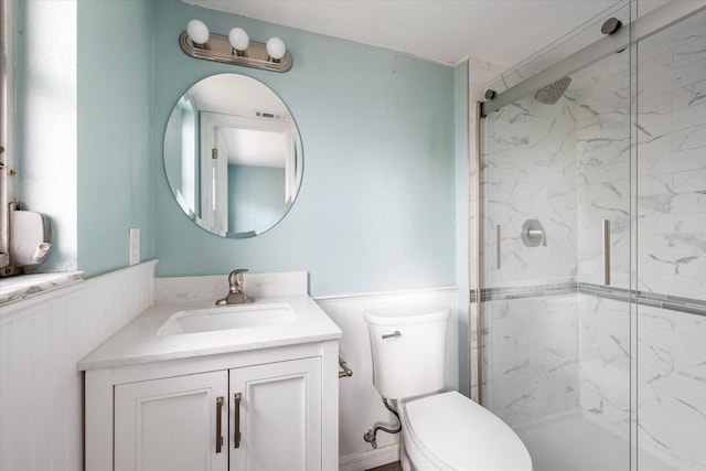 bathroom with a marble finish shower, visible vents, wainscoting, toilet, and vanity