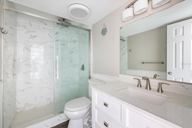 full bathroom with a marble finish shower, wainscoting, vanity, and toilet