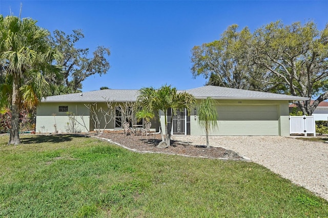 ranch-style house with a garage, fence, driveway, stucco siding, and a front yard