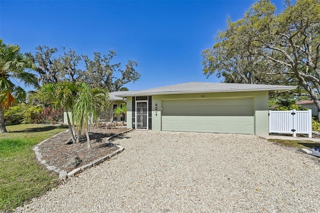 view of front of home featuring gravel driveway, an attached garage, and stucco siding