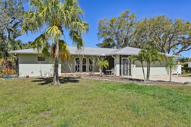 single story home with a front yard, gravel driveway, an attached garage, and stucco siding