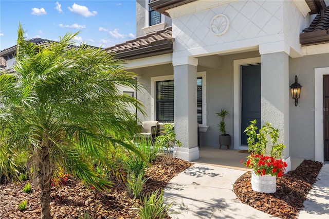 property entrance with covered porch, a tiled roof, and stucco siding