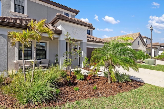 mediterranean / spanish home featuring a garage, driveway, a tiled roof, and stucco siding