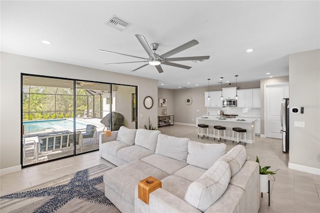 living room with baseboards, visible vents, a sunroom, ceiling fan, and recessed lighting