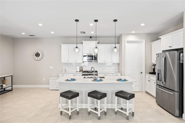 kitchen with decorative backsplash, appliances with stainless steel finishes, a kitchen breakfast bar, light countertops, and a sink