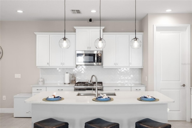 kitchen featuring backsplash, appliances with stainless steel finishes, light countertops, and a breakfast bar area