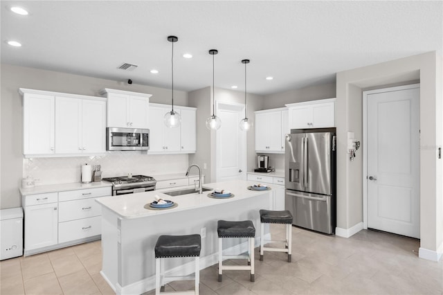 kitchen with a center island with sink, appliances with stainless steel finishes, decorative light fixtures, light countertops, and a sink