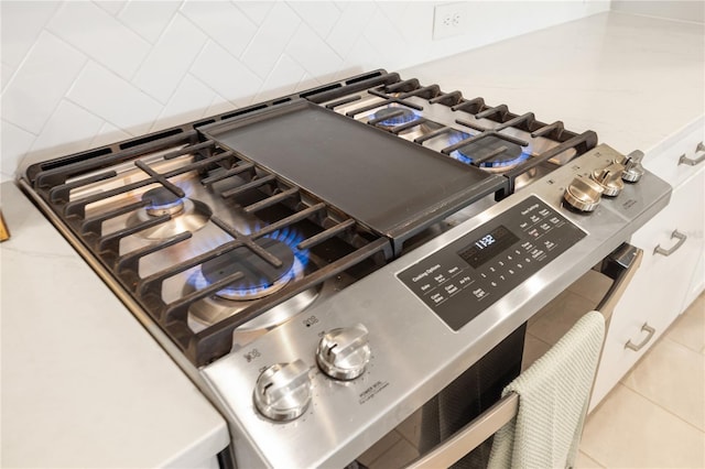 room details featuring light stone counters, backsplash, and gas range