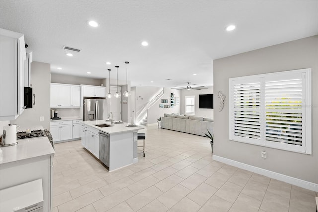 kitchen featuring a breakfast bar, visible vents, appliances with stainless steel finishes, open floor plan, and a sink