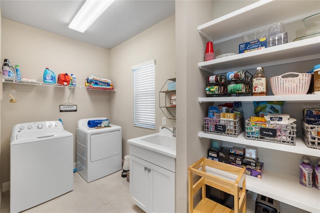 clothes washing area with a textured ceiling, laundry area, a sink, and washer and dryer