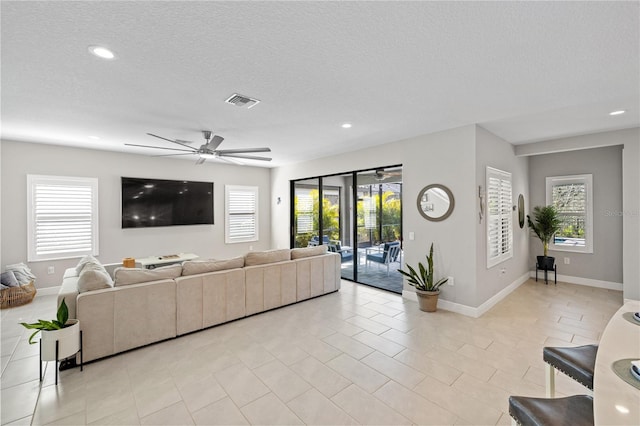 living room with a textured ceiling, baseboards, visible vents, and recessed lighting