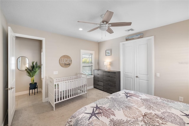 bedroom featuring a ceiling fan, visible vents, light carpet, and baseboards