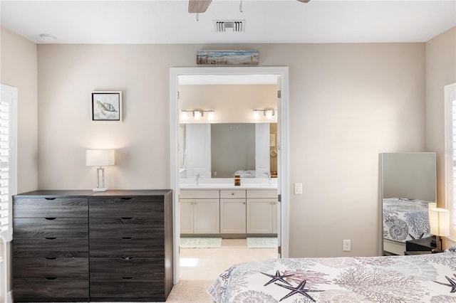 bedroom featuring ensuite bathroom, light tile patterned floors, a sink, and visible vents