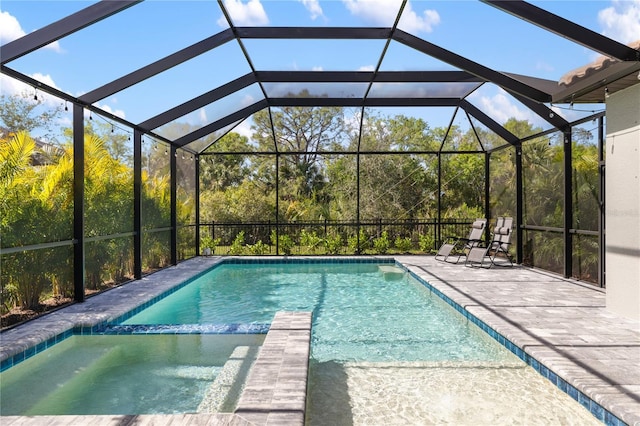 view of swimming pool with a patio, glass enclosure, and a pool with connected hot tub