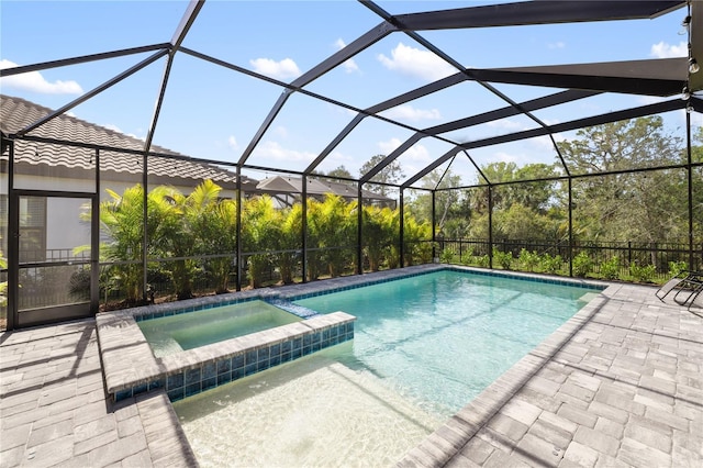 view of swimming pool featuring glass enclosure, a pool with connected hot tub, and a patio area