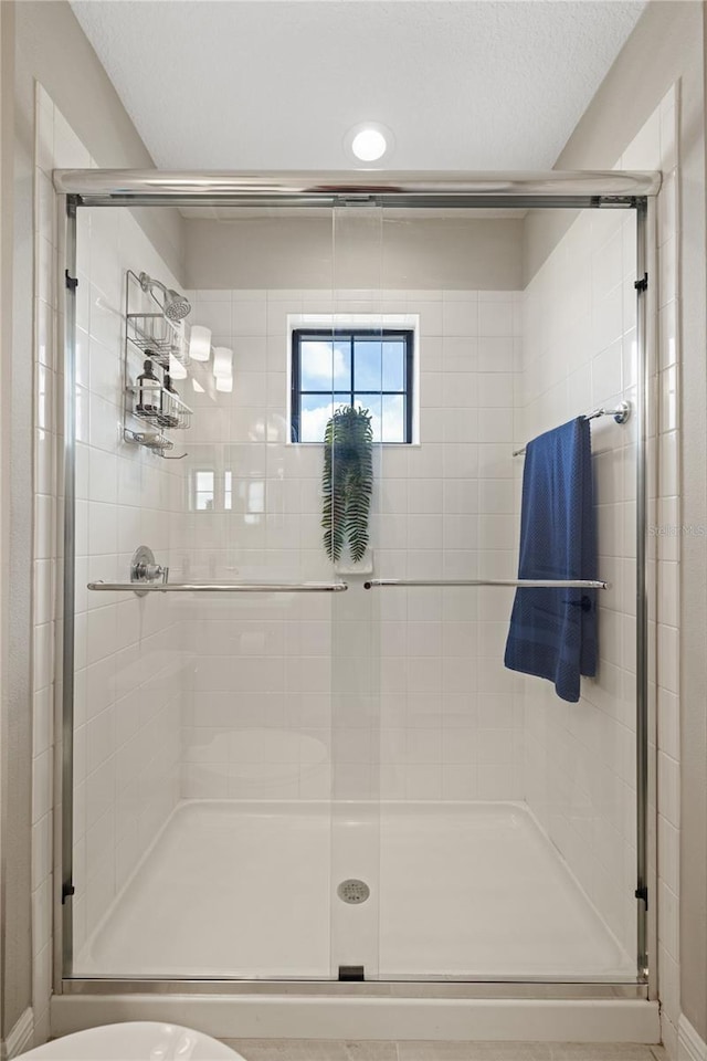 full bathroom with a shower stall and a textured ceiling