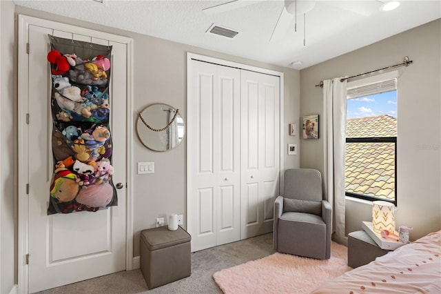 carpeted bedroom with a closet, visible vents, and a ceiling fan