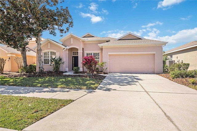 view of front of home with a front yard, driveway, an attached garage, and stucco siding