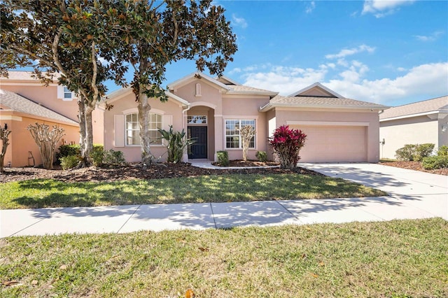 view of front of house with a garage, driveway, a front lawn, and stucco siding