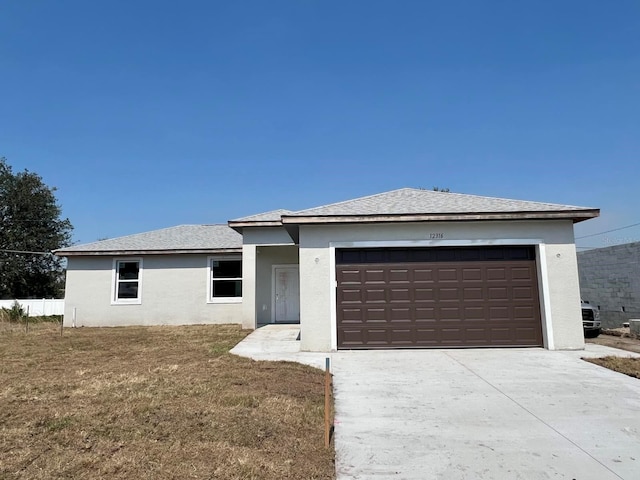 view of front of property with a garage, driveway, a front lawn, and stucco siding