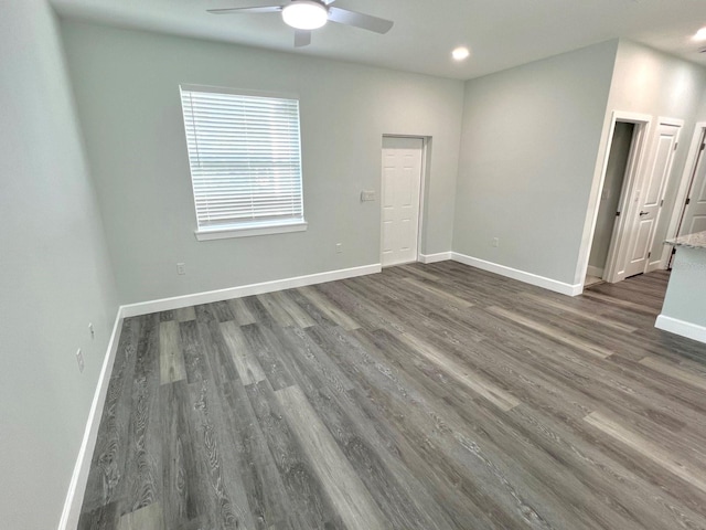 unfurnished room with a ceiling fan, dark wood-style flooring, and baseboards