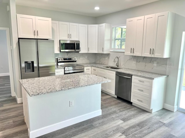 kitchen featuring appliances with stainless steel finishes, a sink, white cabinetry, and tasteful backsplash