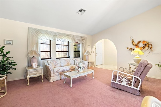 carpeted living area with visible vents, arched walkways, and baseboards