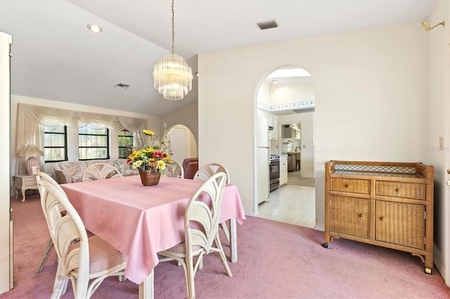 dining space with visible vents, arched walkways, light carpet, and an inviting chandelier