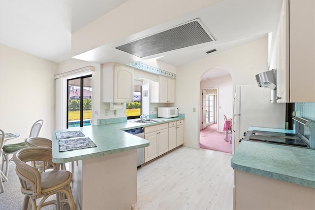 kitchen featuring a sink, stainless steel dishwasher, arched walkways, a peninsula, and white microwave