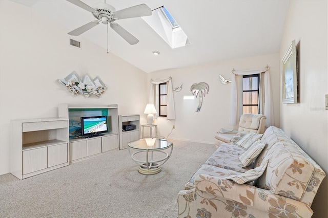 living area featuring visible vents, ceiling fan, carpet flooring, vaulted ceiling with skylight, and a fireplace