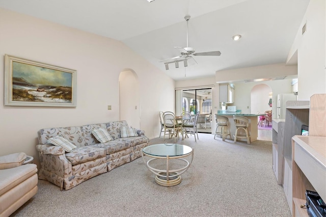 living room with lofted ceiling, a ceiling fan, arched walkways, and light carpet