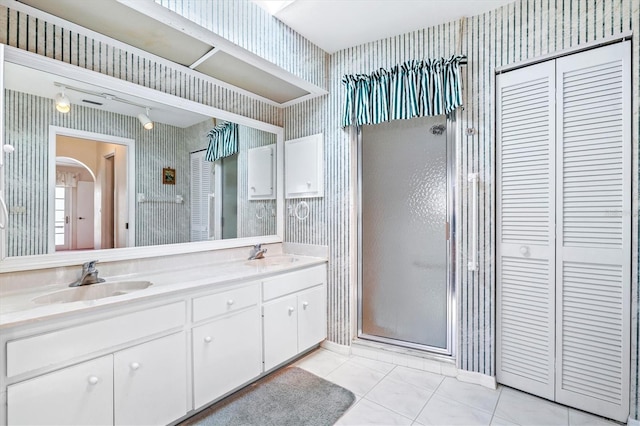 full bathroom featuring a sink, a closet, a shower stall, and wallpapered walls