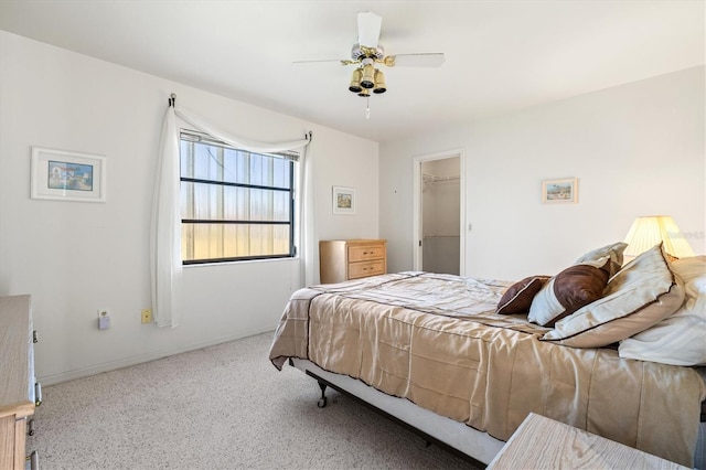 bedroom with a walk in closet, a ceiling fan, and baseboards