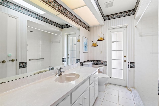 bathroom with tile patterned floors, visible vents, a tile shower, and wallpapered walls