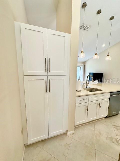 bar featuring visible vents, stainless steel dishwasher, a sink, and decorative light fixtures