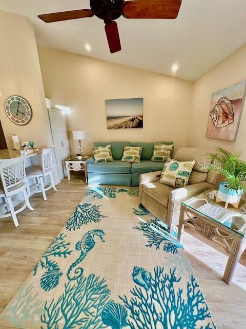 living room featuring lofted ceiling, wood finished floors, a ceiling fan, and recessed lighting