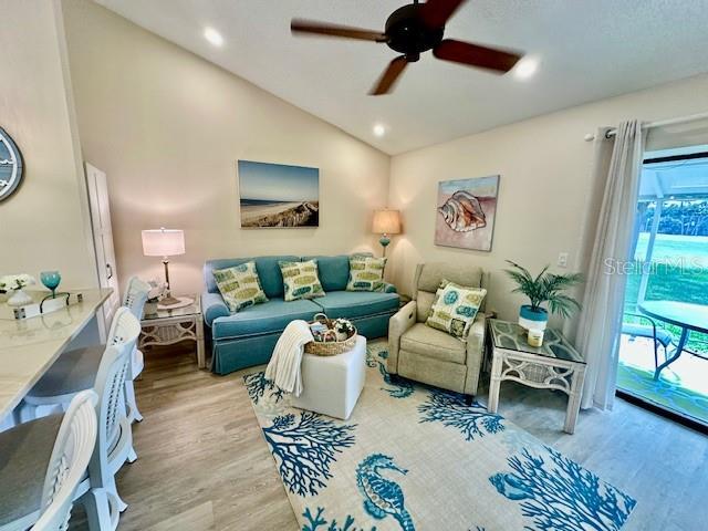 living room featuring lofted ceiling, ceiling fan, wood finished floors, and recessed lighting