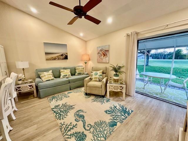 living area with vaulted ceiling, ceiling fan, and wood finished floors