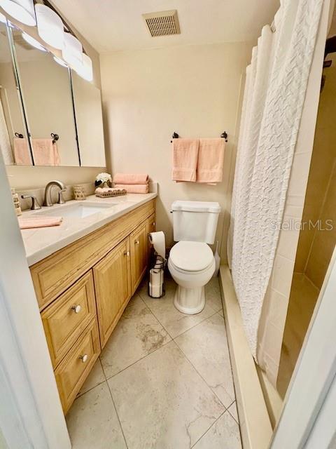 bathroom with toilet, vanity, visible vents, and a shower with curtain