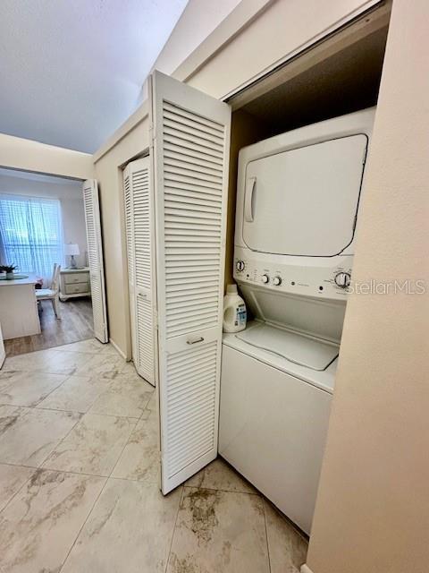 clothes washing area with laundry area and stacked washing maching and dryer