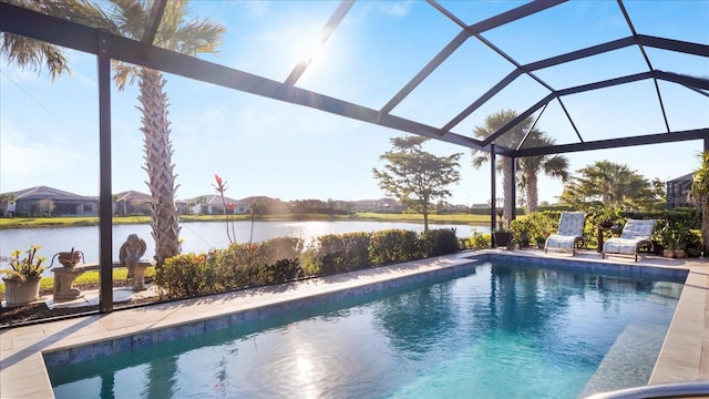 pool with glass enclosure, a patio, and a water view