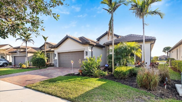 view of front of house featuring an attached garage, a tile roof, decorative driveway, and stucco siding