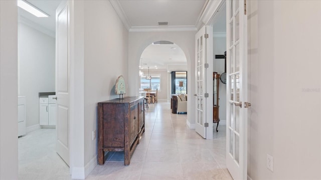 hall featuring baseboards, visible vents, arched walkways, crown molding, and french doors