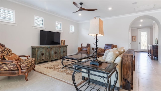 living room featuring arched walkways, light tile patterned floors, and ornamental molding