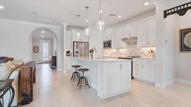 kitchen featuring arched walkways, under cabinet range hood, visible vents, built in microwave, and stainless steel fridge