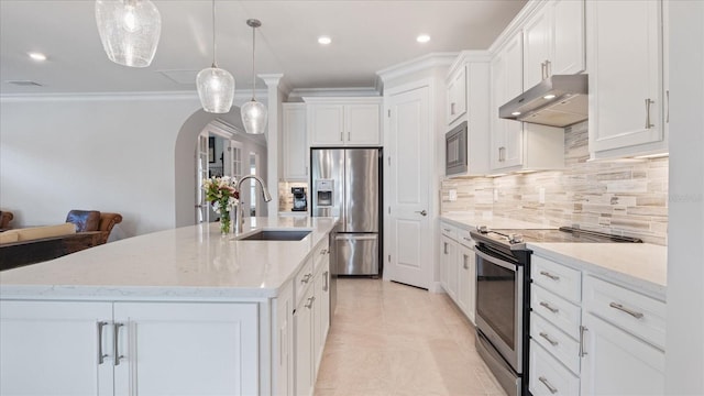 kitchen with arched walkways, stainless steel appliances, tasteful backsplash, a sink, and under cabinet range hood