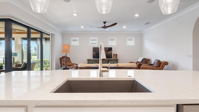 kitchen with crown molding, arched walkways, open floor plan, and a sink