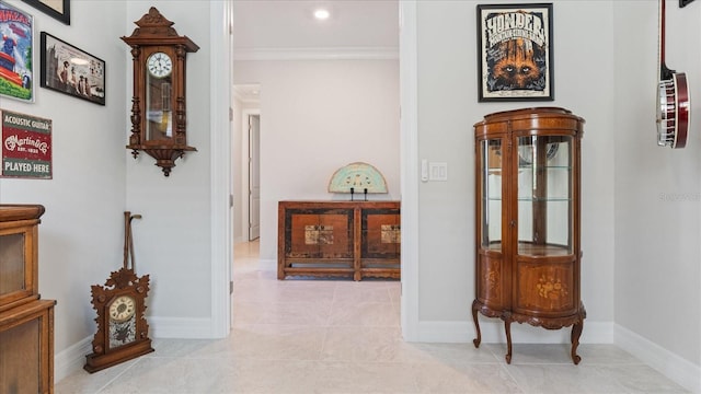 corridor with light tile patterned floors, ornamental molding, and baseboards